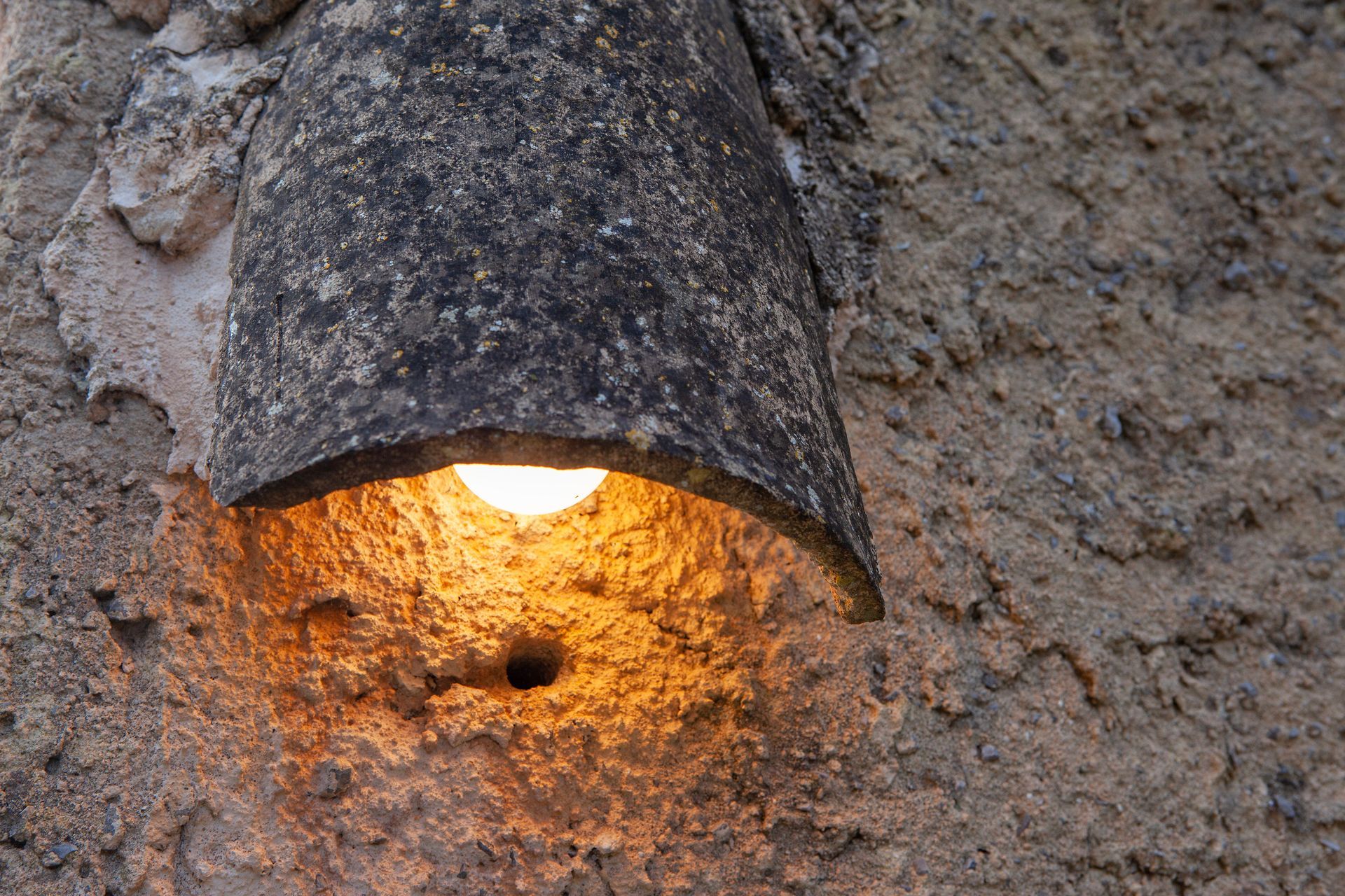 A light is shining through a hole in a wall.