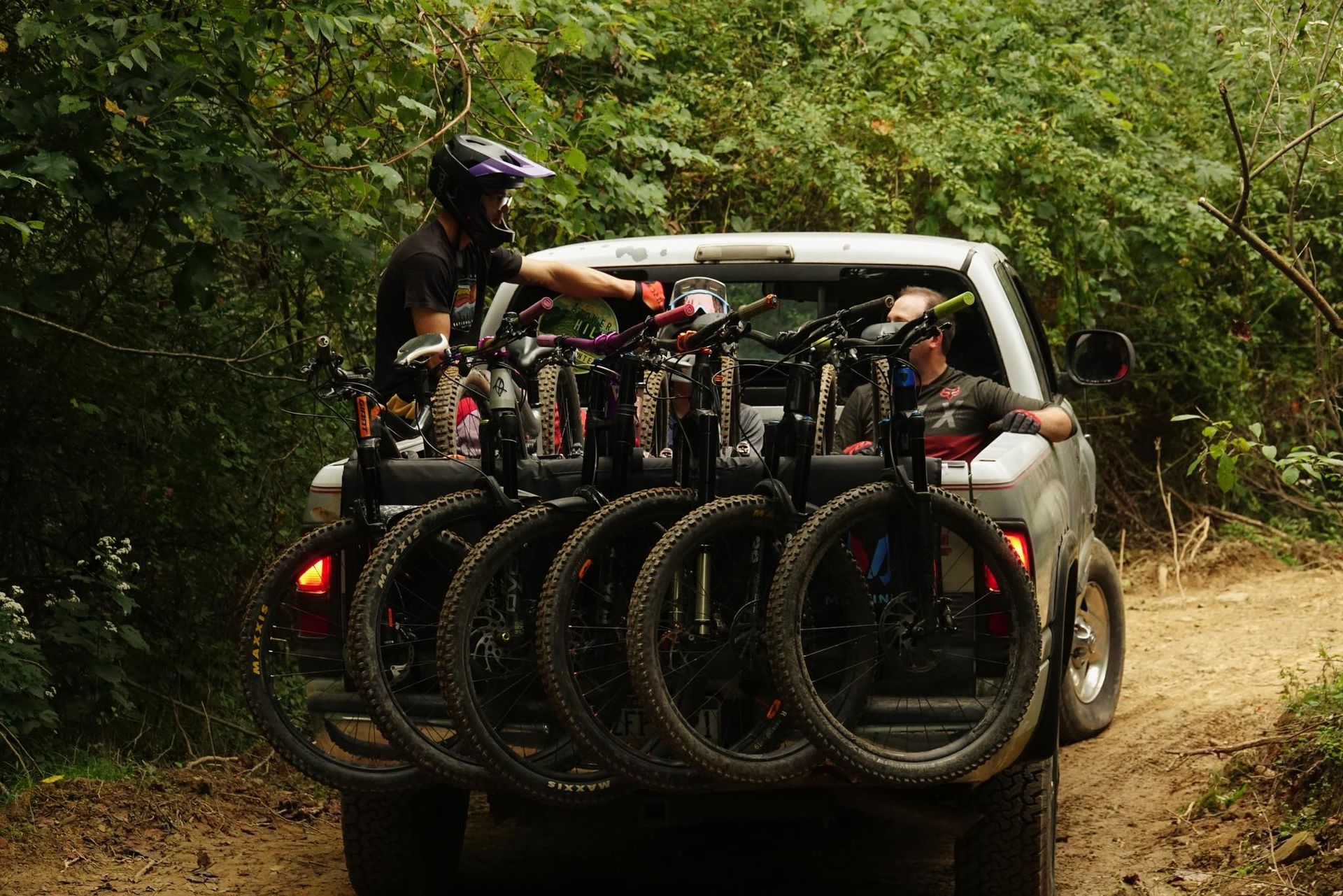 mountain bike riders in the woods n the back of a truck