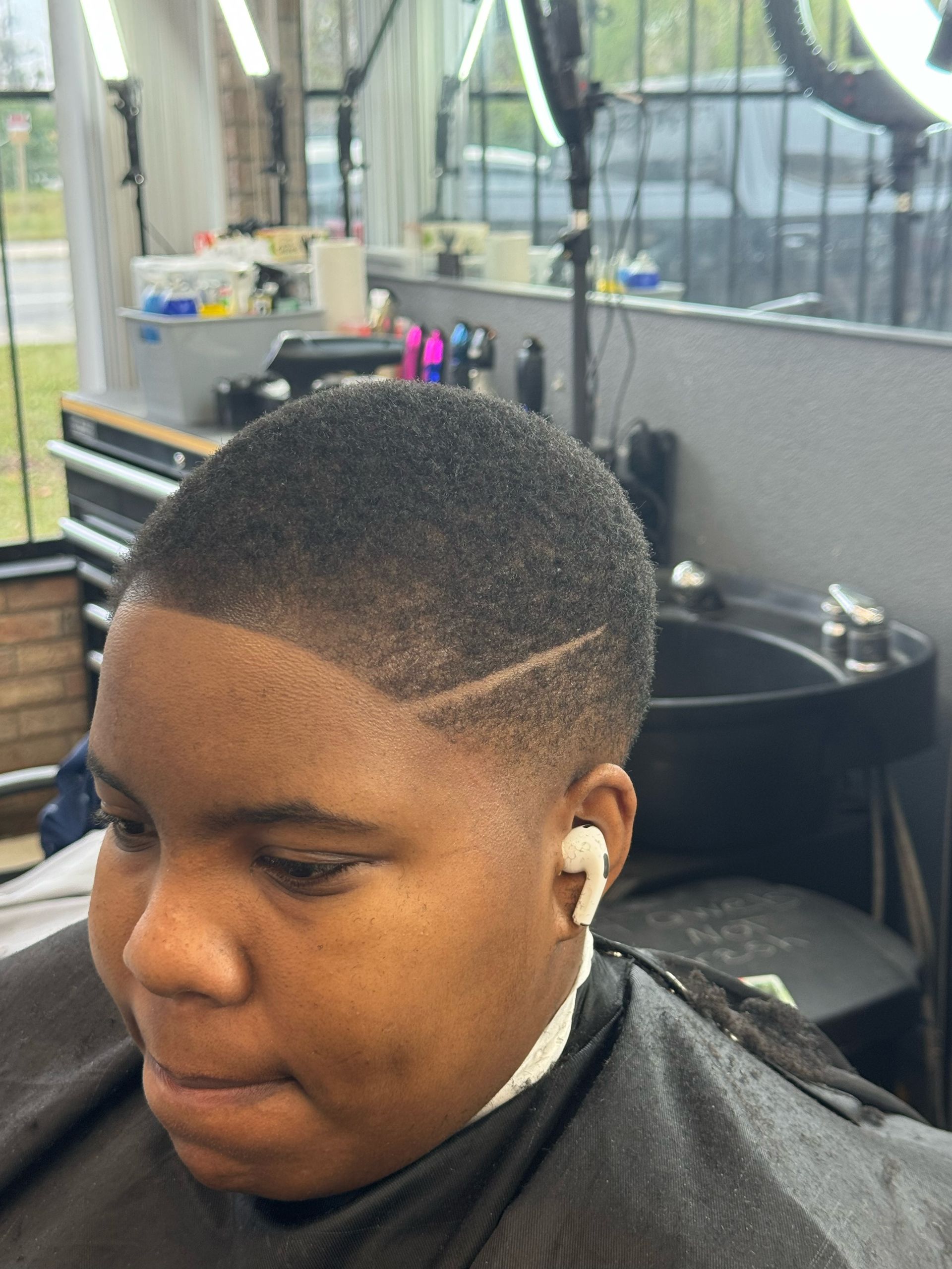 A young boy is getting his hair cut at a barber shop.
