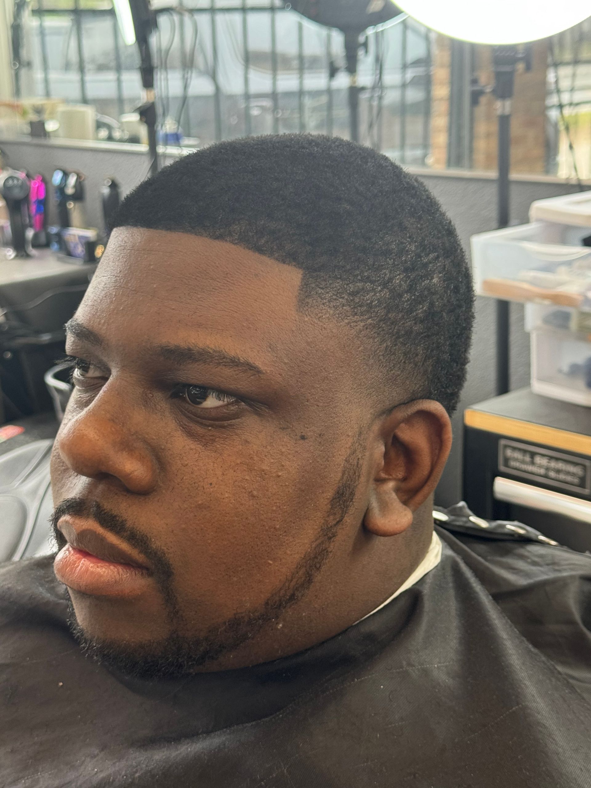 A man with a beard is getting his hair cut at a barber shop.