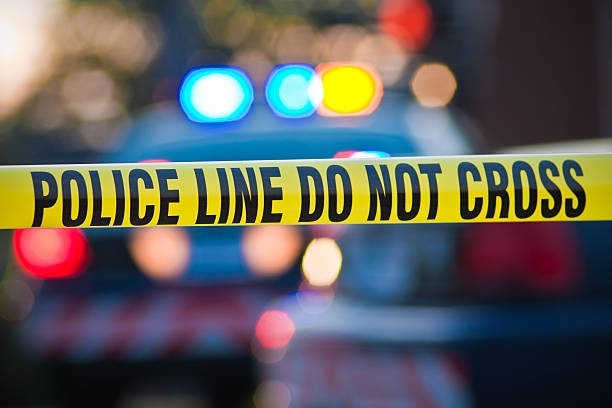A police tape says police line do not cross in front of a police car.