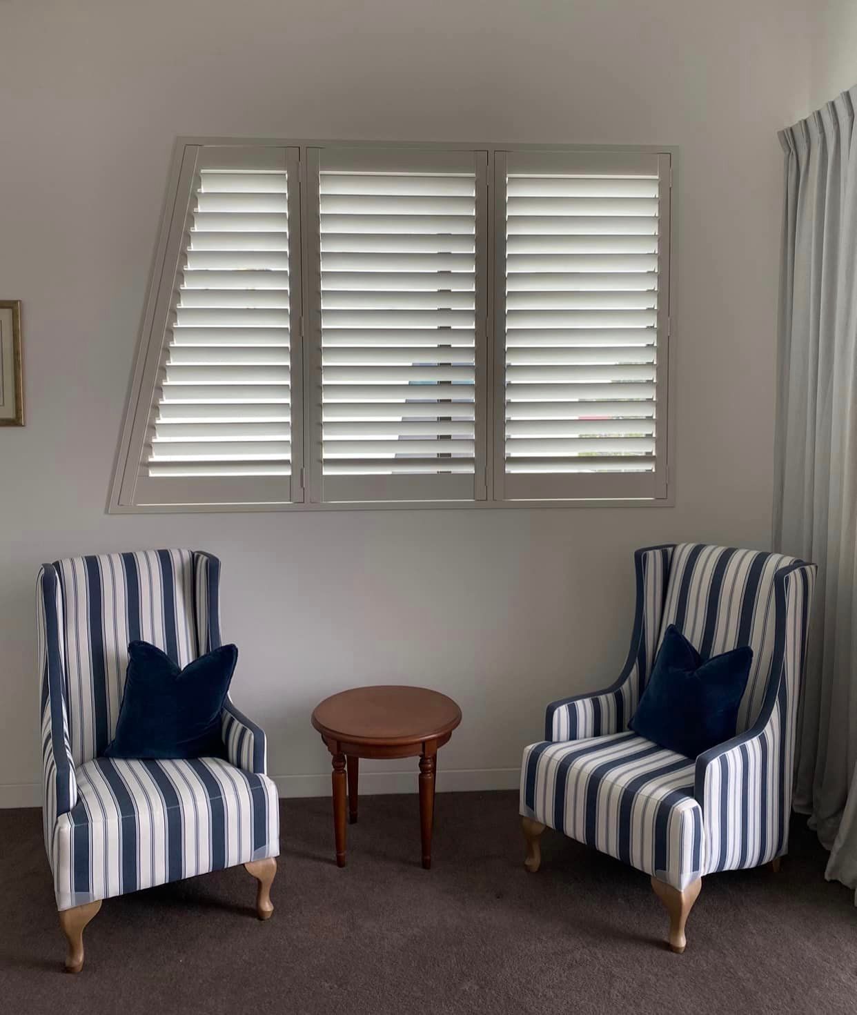 Two Striped Chairs Sit In Front Of A Window With Shutters — Shutters in Gold Coast, QLD