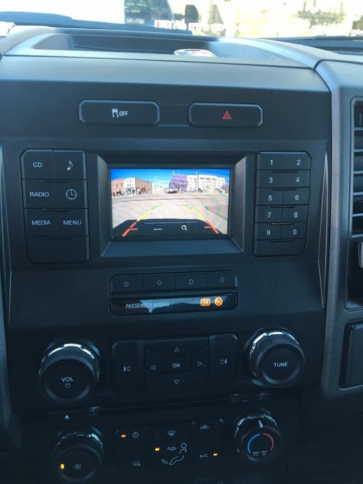 Car dashboard center console with touchscreen backup camera display and climate controls.
