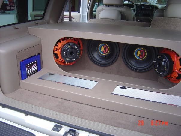 Custom car audio setup with orange speakers mounted in a beige dashboard