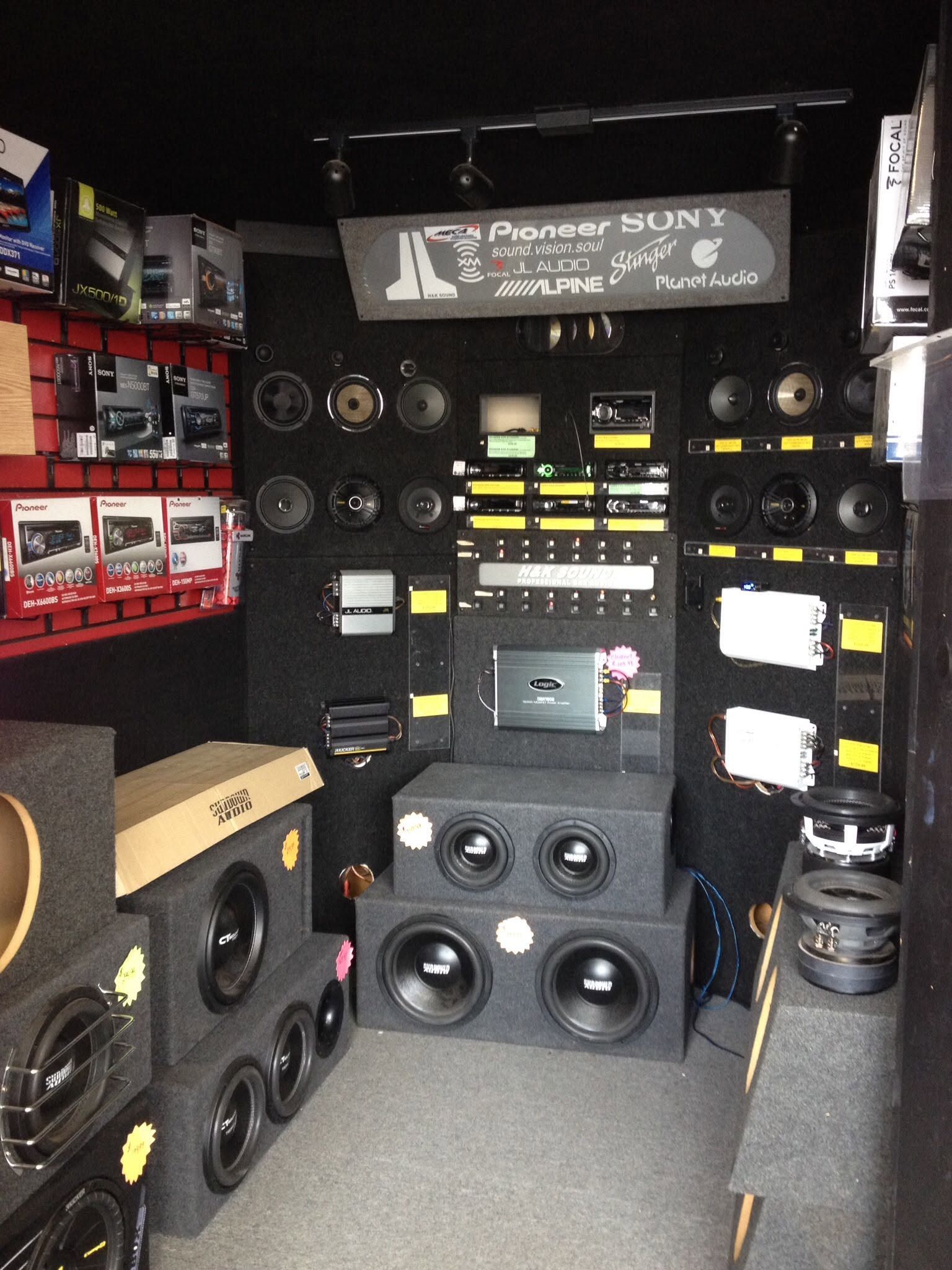 Display of Sony car audio speakers and subwoofers in a store showroom, with stacked black speaker boxes.