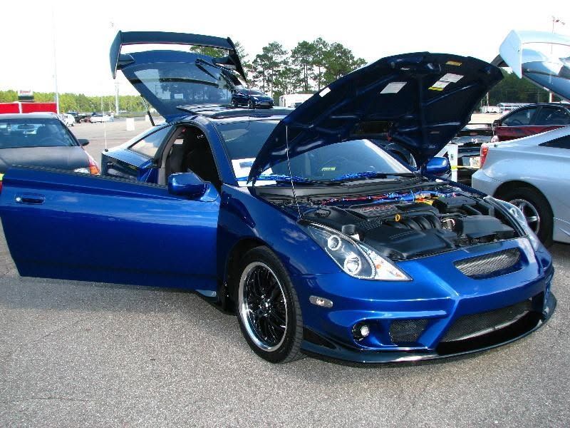 Blue sports car with hood and doors open at a car show