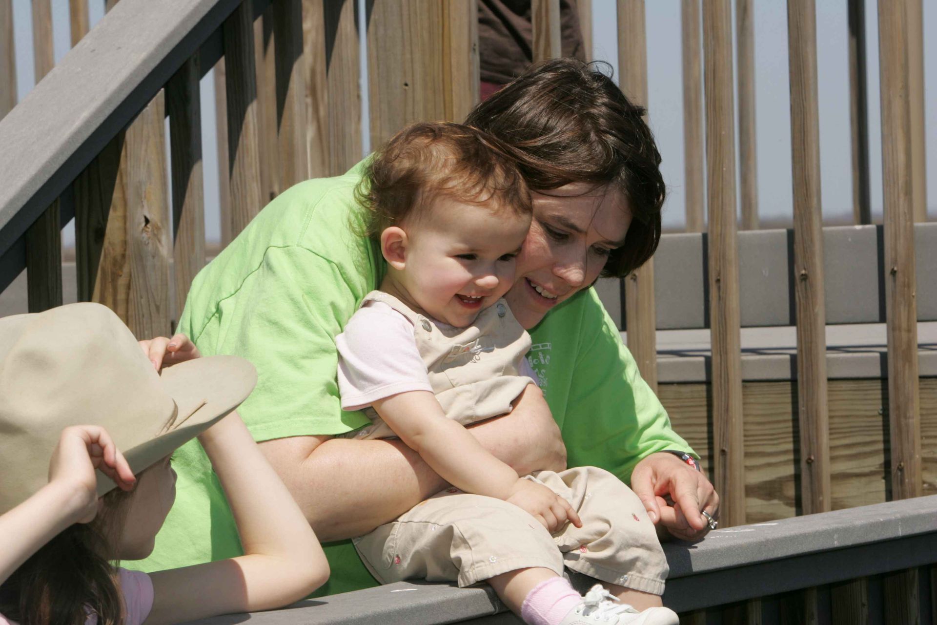 A woman in a green shirt is holding a baby
