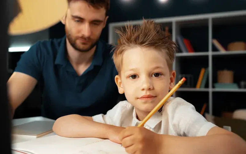 A man is helping a young boy with his homework.