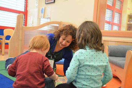 A woman is reading a book to two children in a classroom.