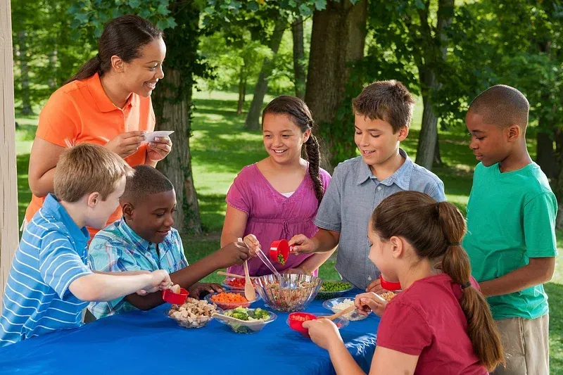A group of children are sitting around a table eating food.