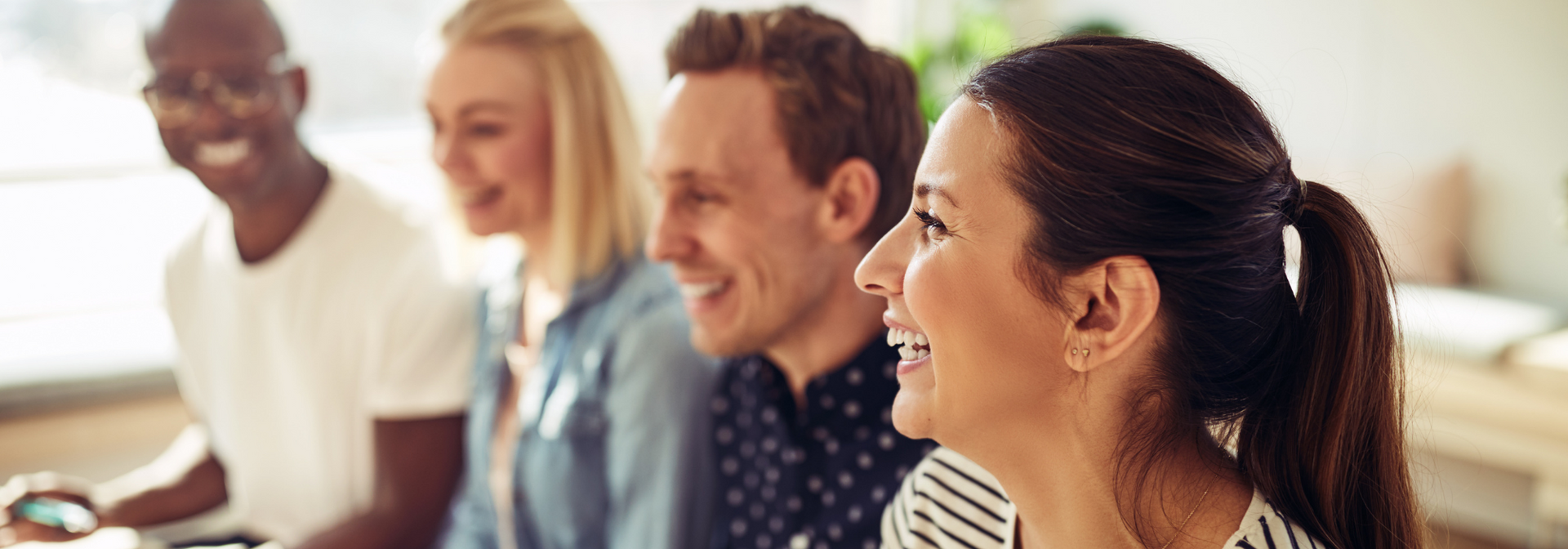 Smiling coworkers in a bright office, seated together in conversation