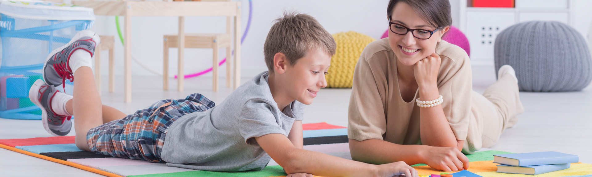 Woman and child lying on a play mat, smiling and playing with colorful blocks in a bright room