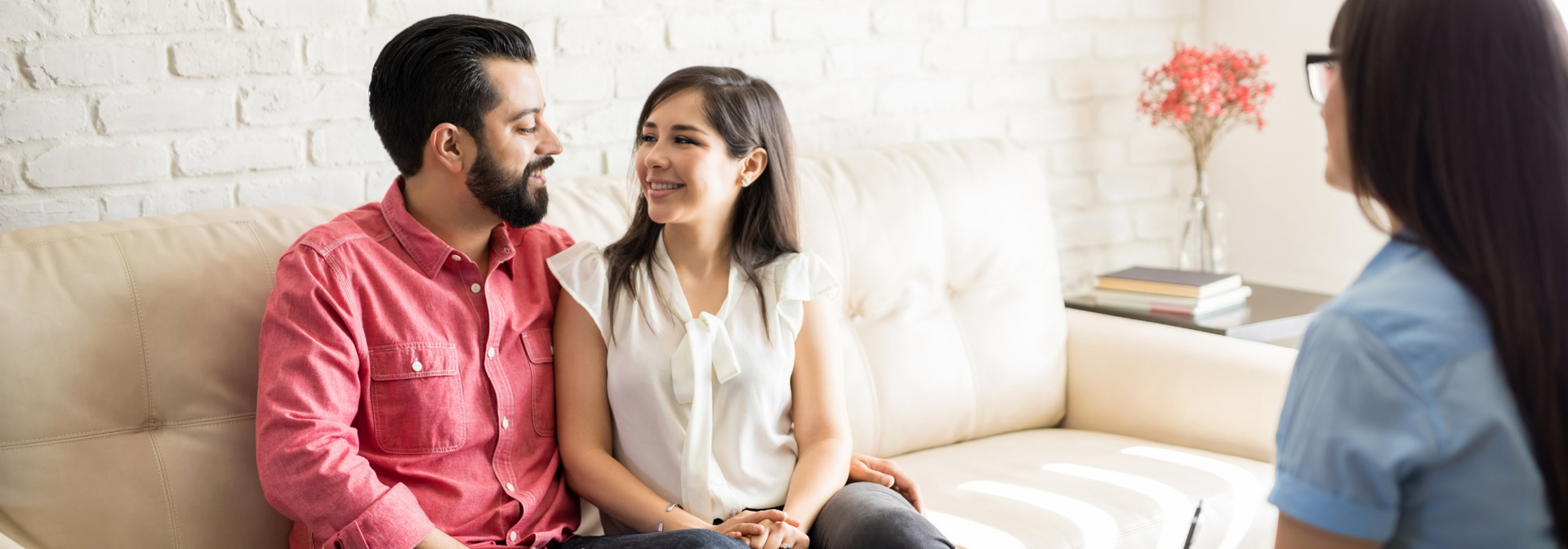 Two people sitting on a couch, smiling and talking in a bright living room