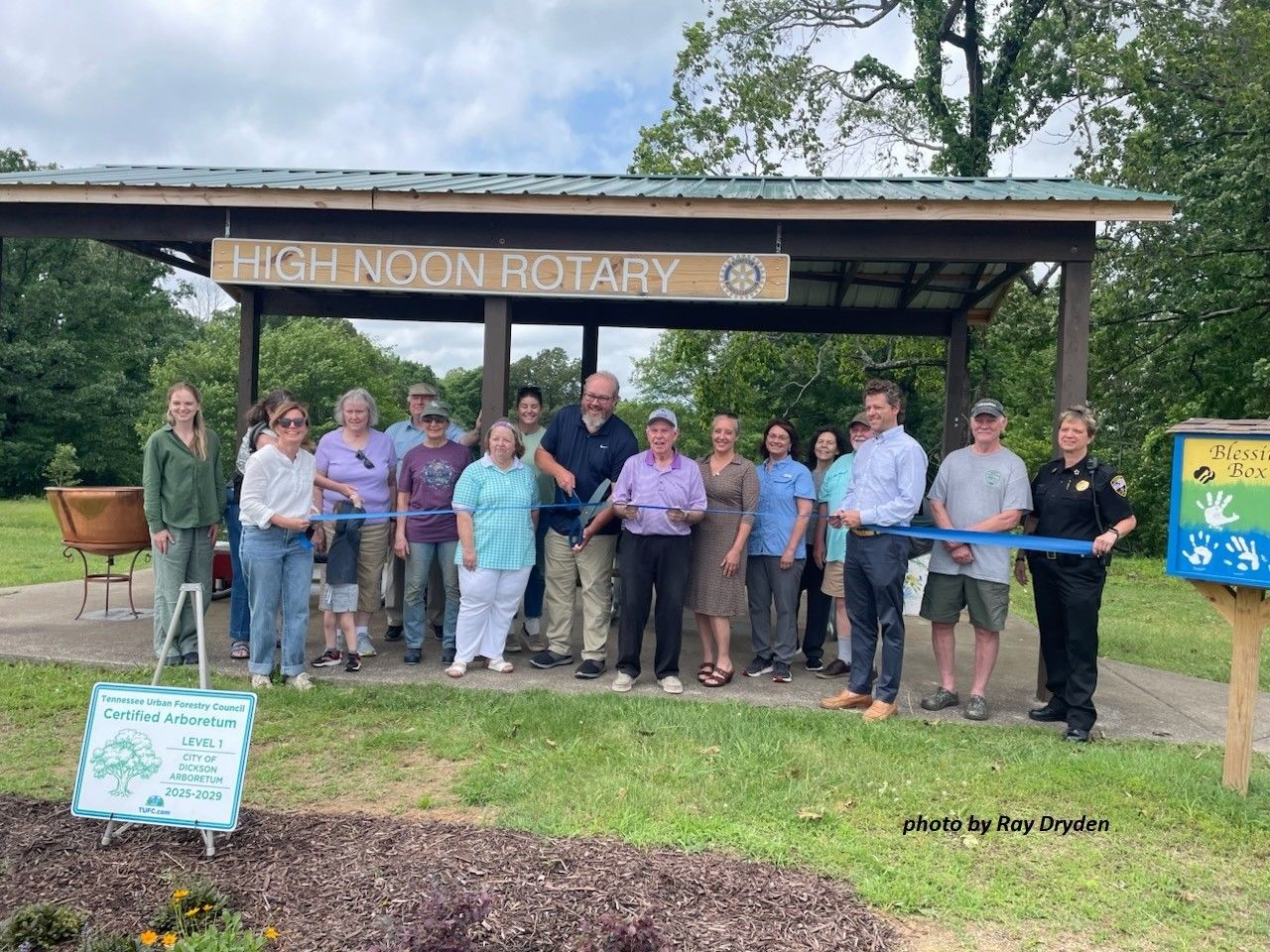 Group of people posing under the High Noon Rotary sign at a park entrance
