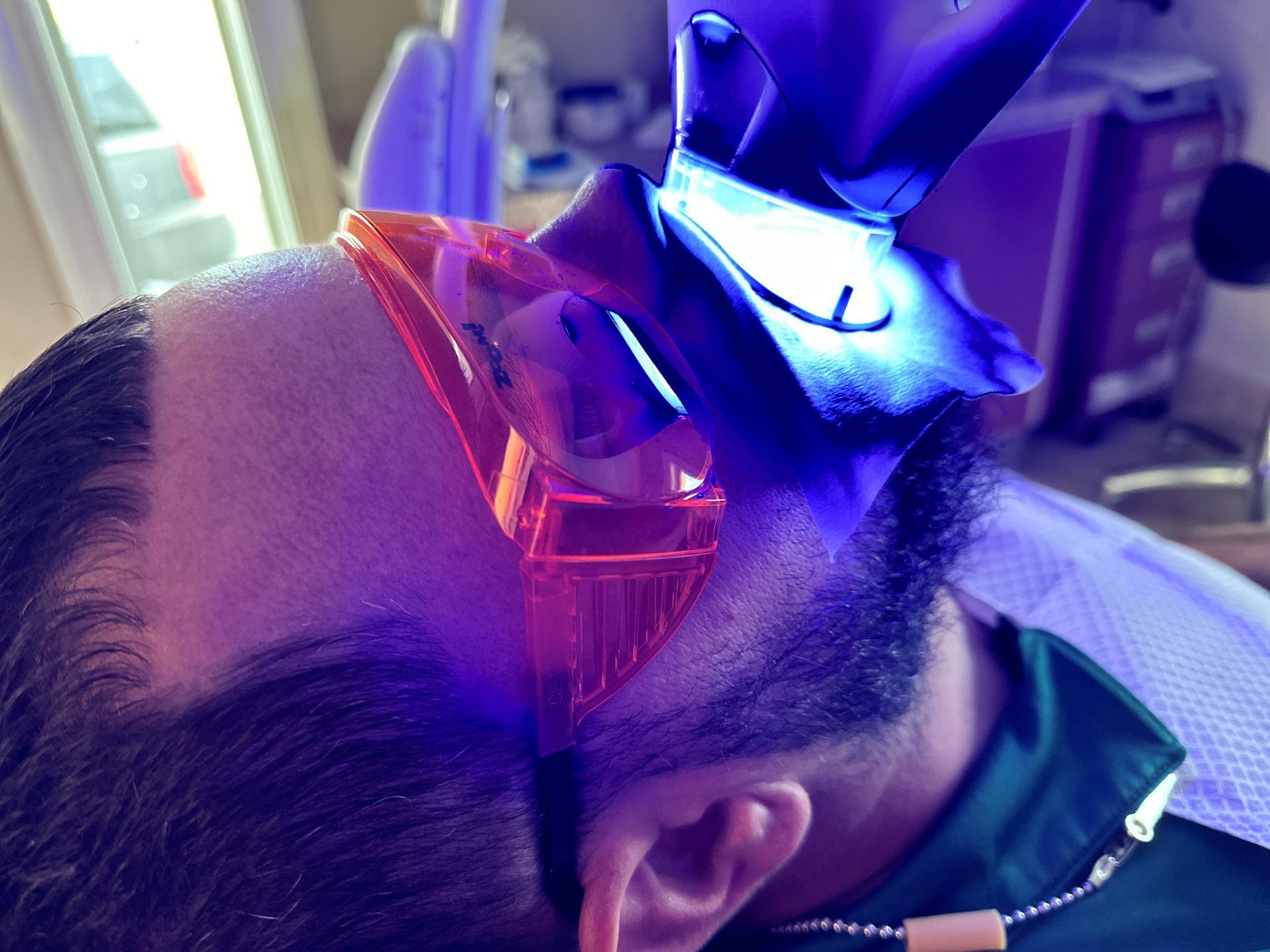 Person with red and blue laser goggles near their face, lying down in purple light.