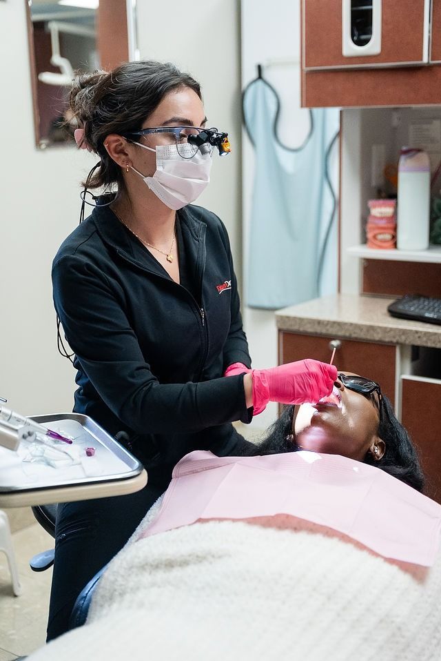 Dentist wearing gloves treats a patient in a dental chair