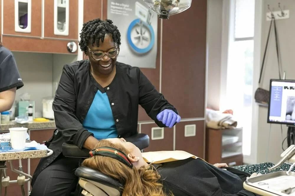 Dentist examining a patient in a dental chair, wearing purple gloves in a clinic.