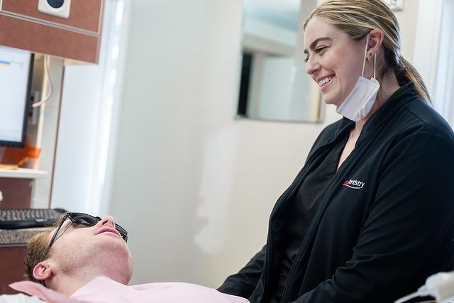 Dental professional smiling with patient in exam chair