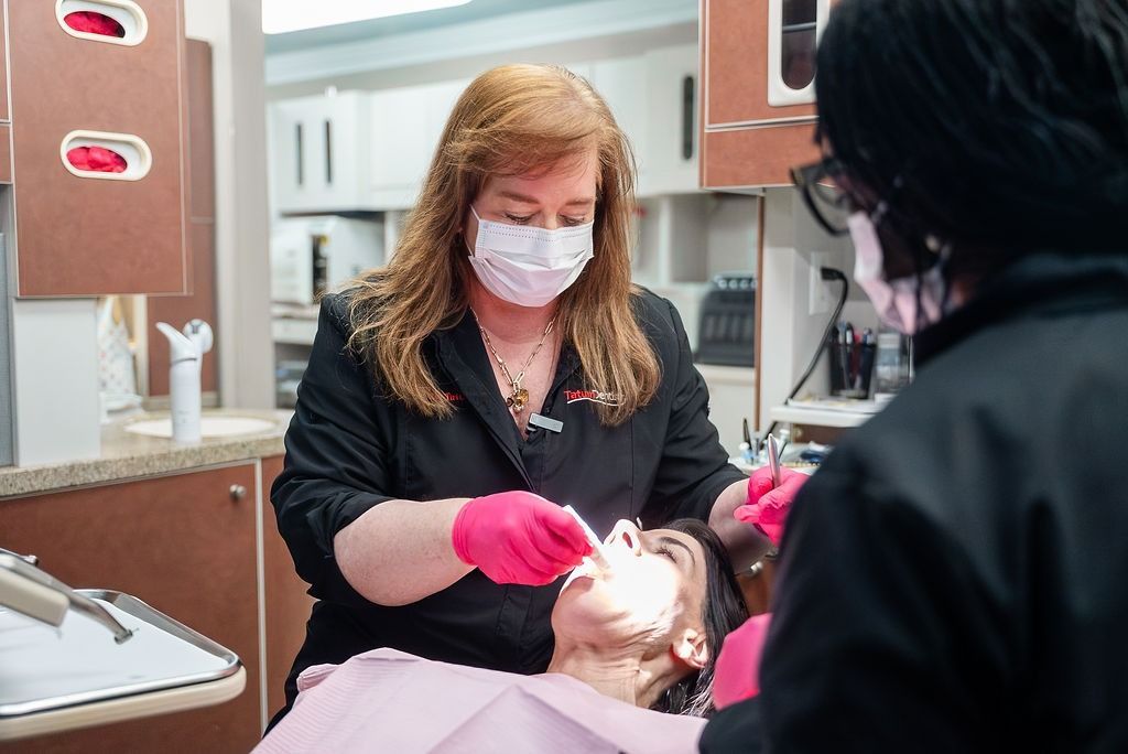 Dentist wearing pink gloves examines a patient in a dental clinic.