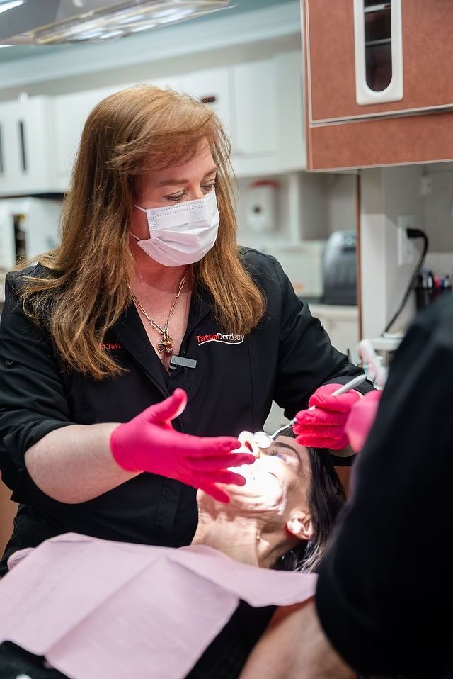 Dentist in pink gloves treating a patient reclining in a dental chair