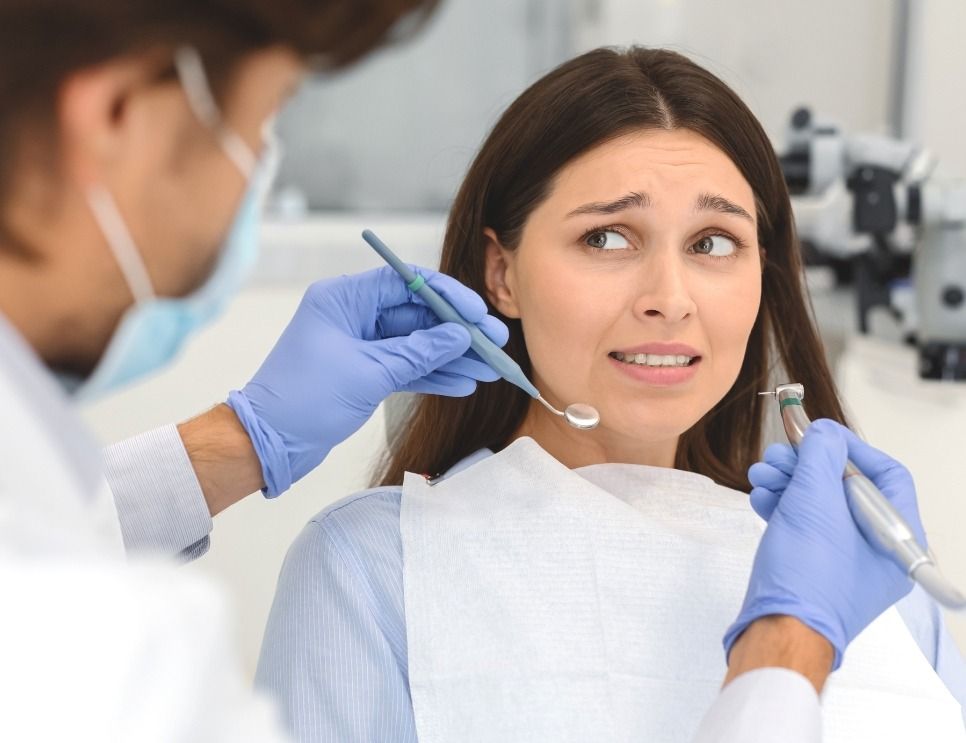 Dentist examining a worried patient with dental tools in a clinic.