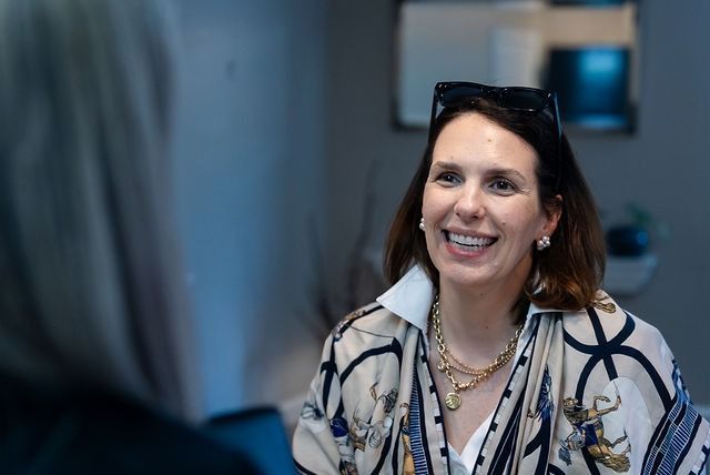 Smiling woman in a patterned jacket speaking indoors