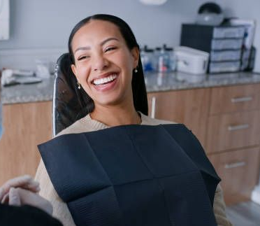 Smiling dental patient in chair wearing a bib