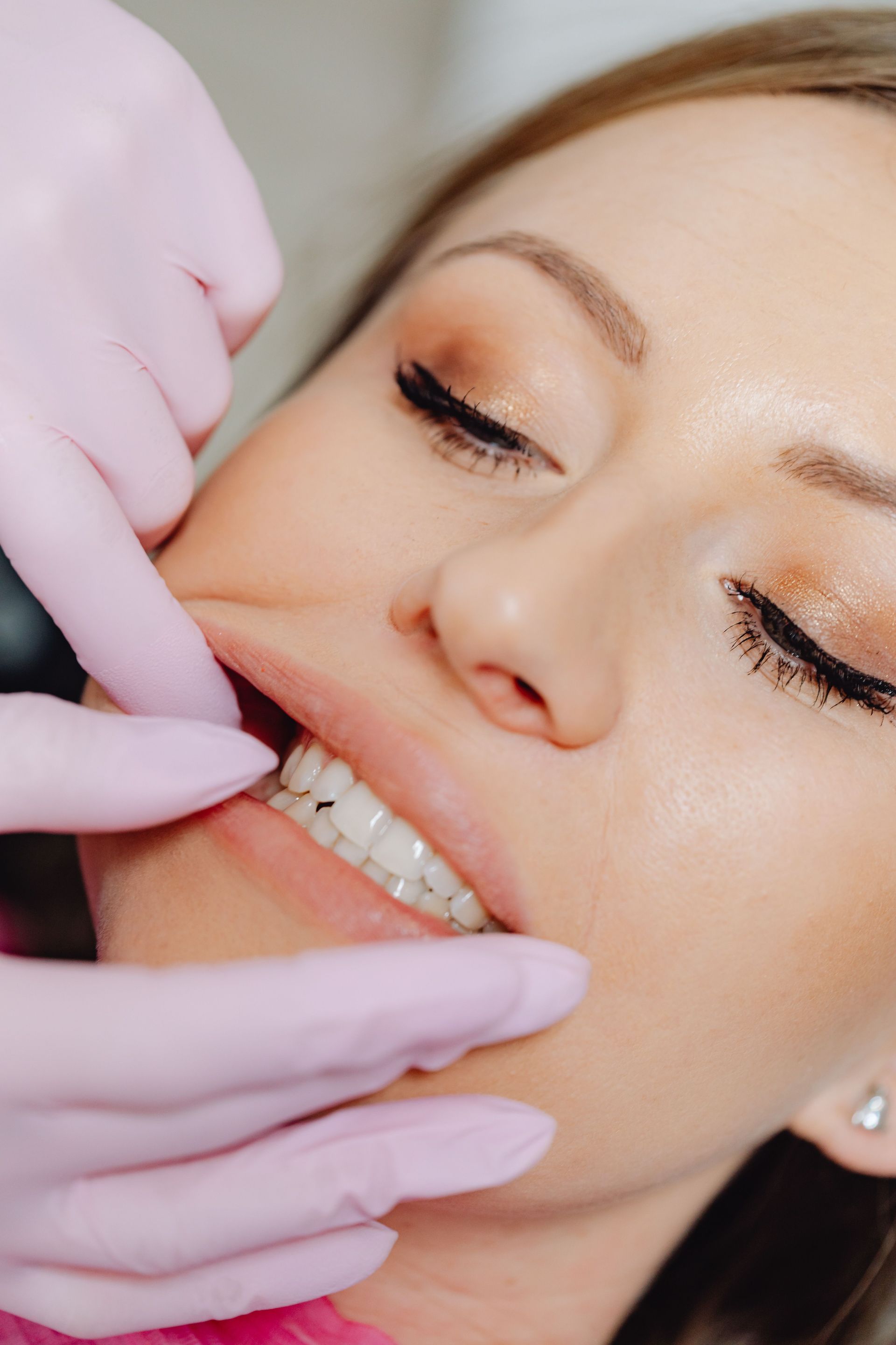 Dentist examining a woman’s teeth with gloved hands close-up