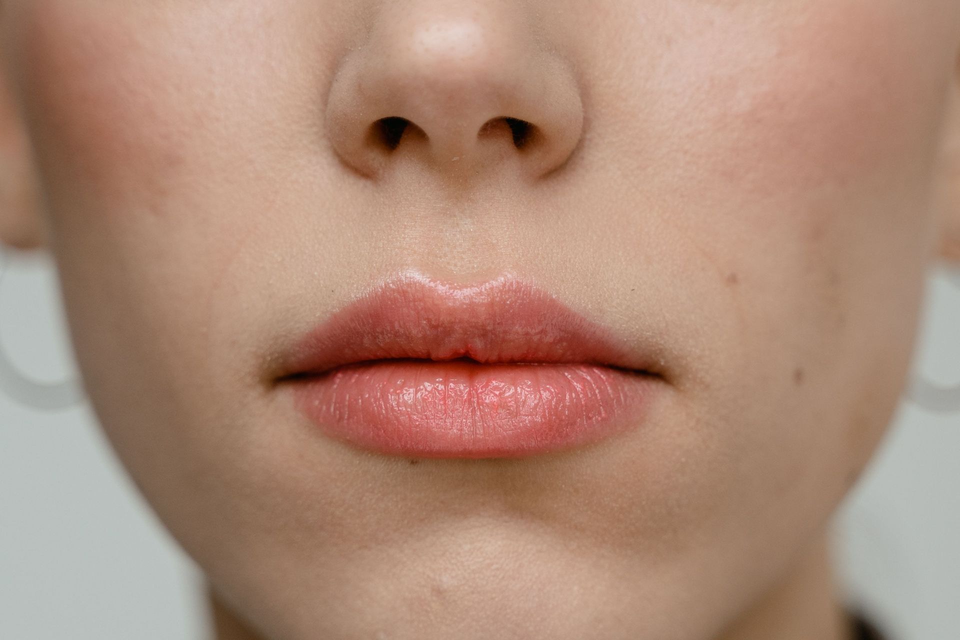 Close-up of a face showing nose and pink lips with a neutral expression