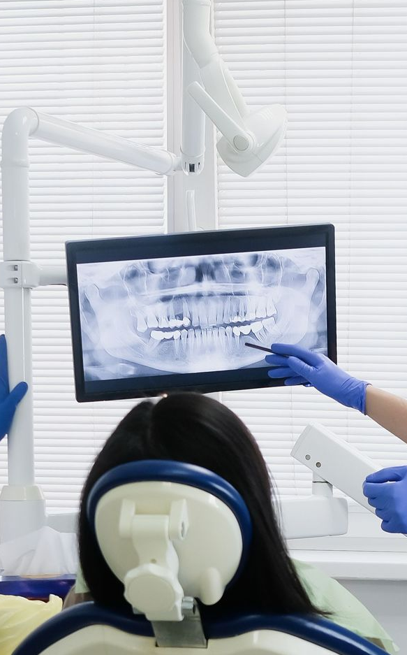 Dentist examining a patient’s teeth on an X-ray monitor in a bright clinic