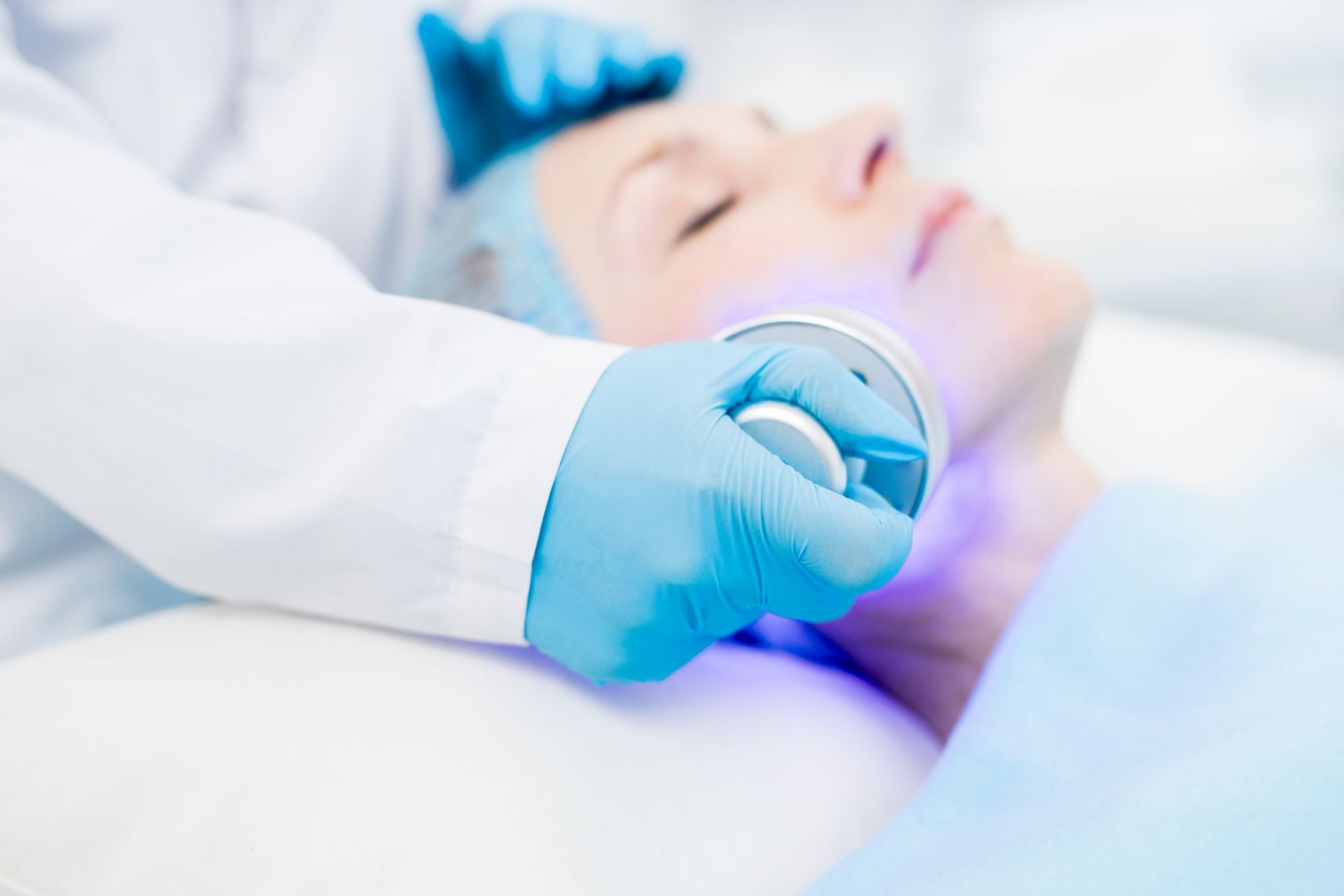 A close-up of a woman’s face being treated with a high-frequency device during a professional facial.