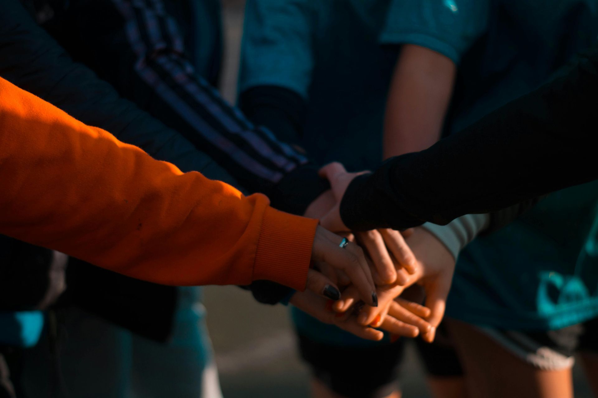 A group holding hands in unity, symbolizing compassionate and supportive oncology-trained estheticians.
