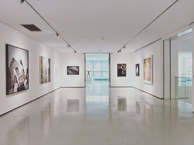 A large empty room with paintings on the walls in a museum.