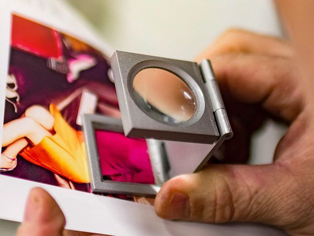 A person is holding a magnifying glass over a piece of paper.