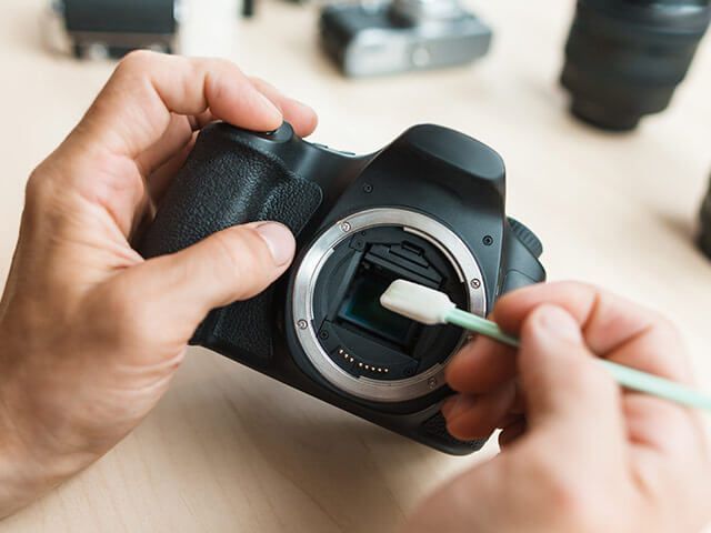 A person is cleaning a camera with a cotton swab.