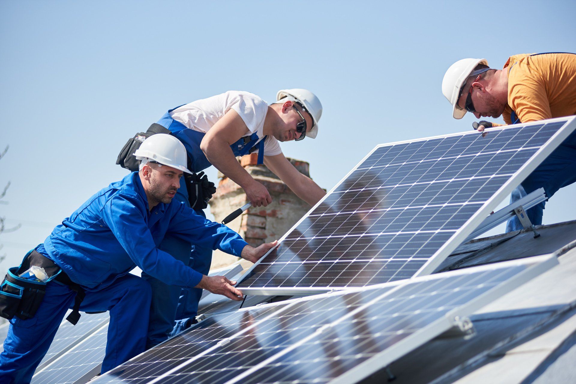 Eine Gruppe von Männern installiert Solarmodule auf einem Dach.