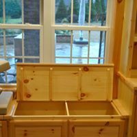 Wooden window seat with open storage compartments below a window.