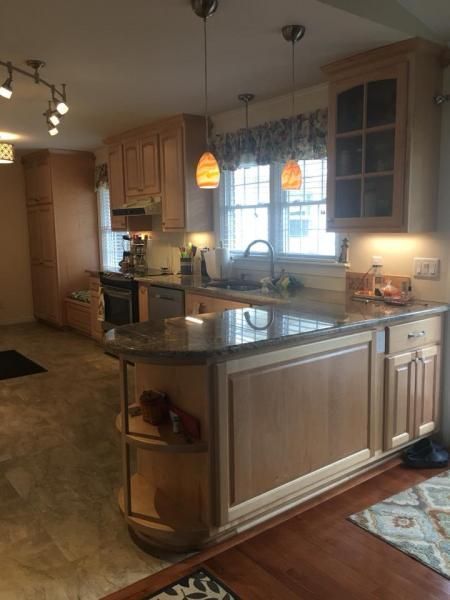 Kitchen with light-colored cabinets, granite countertop, two pendant lights, and tile flooring.