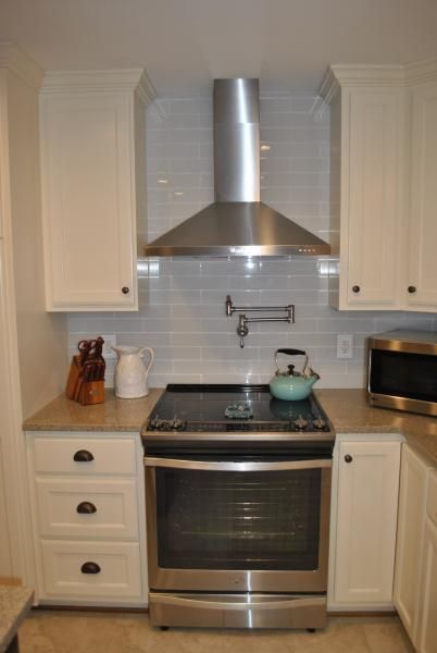 Kitchen with white cabinets, stainless steel range, and range hood.