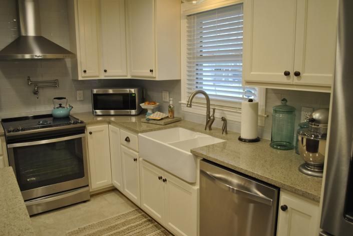 White kitchen with stainless steel appliances, white cabinets, and farmhouse sink.