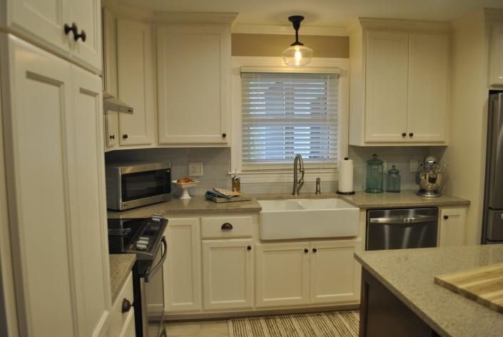 White kitchen with farmhouse sink, stainless steel appliances, and cream-colored cabinets.