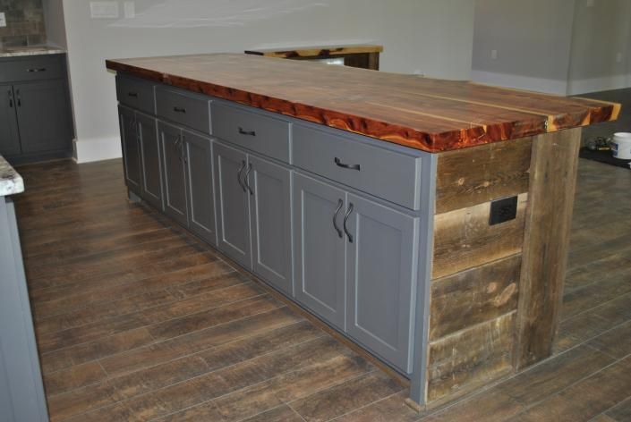 Kitchen island with gray cabinets, wood countertop, and rustic wood accents.