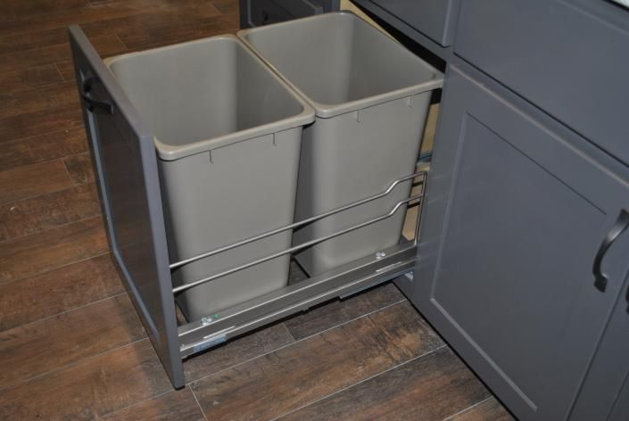 Gray pull-out kitchen trash and recycling bins installed in a gray cabinet, showing the open pull-out frame.