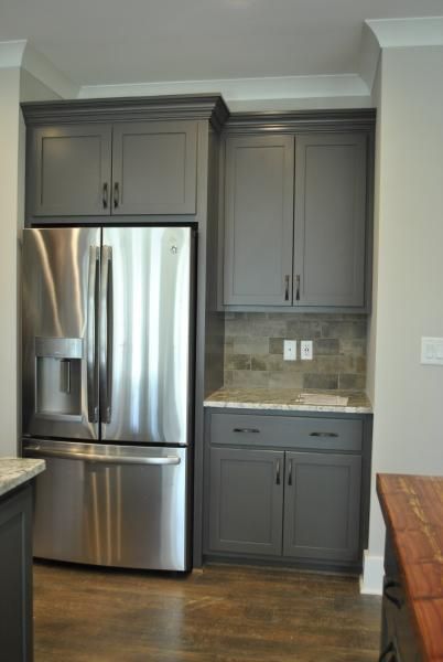 Kitchen with stainless steel refrigerator and gray cabinets. Counter space and tile backsplash are visible.