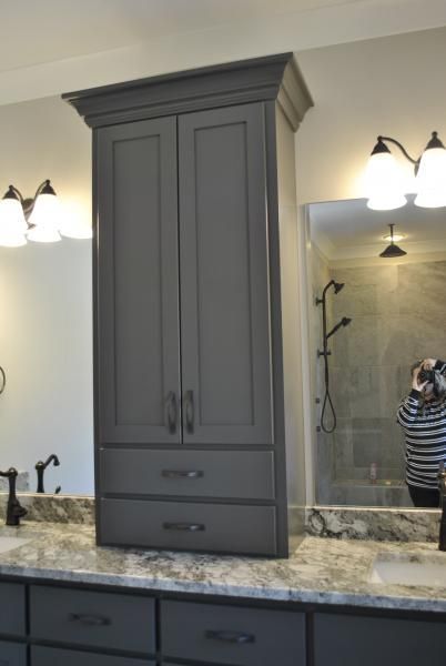 Tall gray bathroom cabinet with doors and drawers over a countertop.