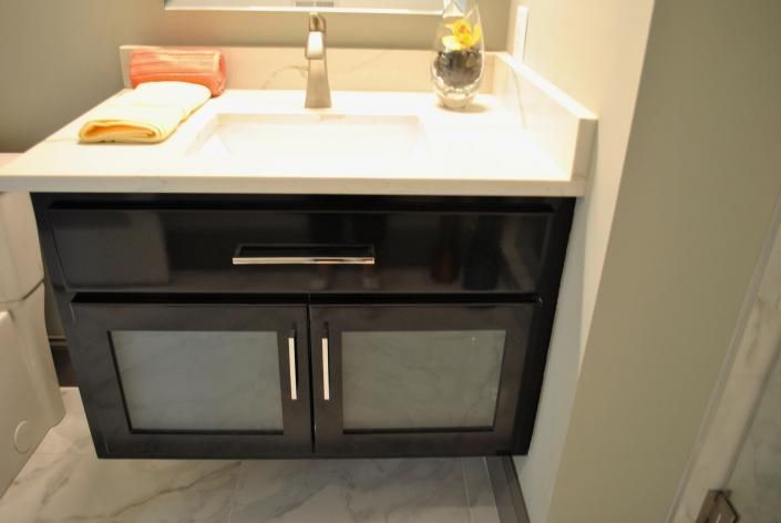 Black bathroom vanity with white countertop, sink, and brushed nickel faucet.