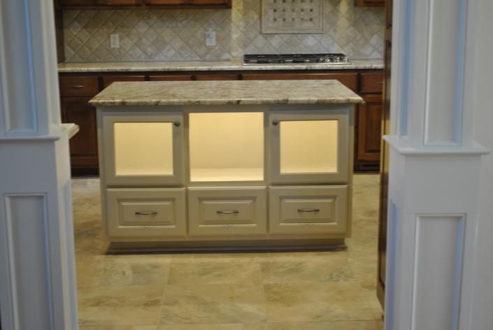 Kitchen island with granite countertop, illuminated cabinet, and drawers.