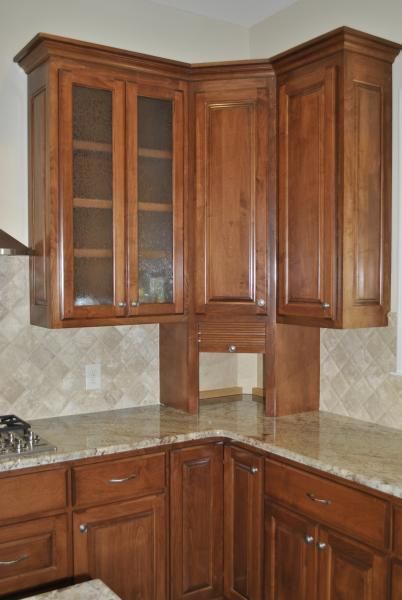Kitchen cabinets in various shades of brown, corner setup with glass-fronted cabinet.