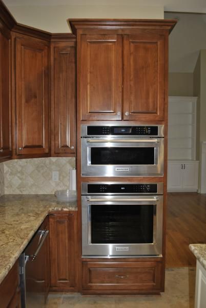 Built-in kitchen appliances, stainless steel microwave oven and oven, inside dark wood cabinets.