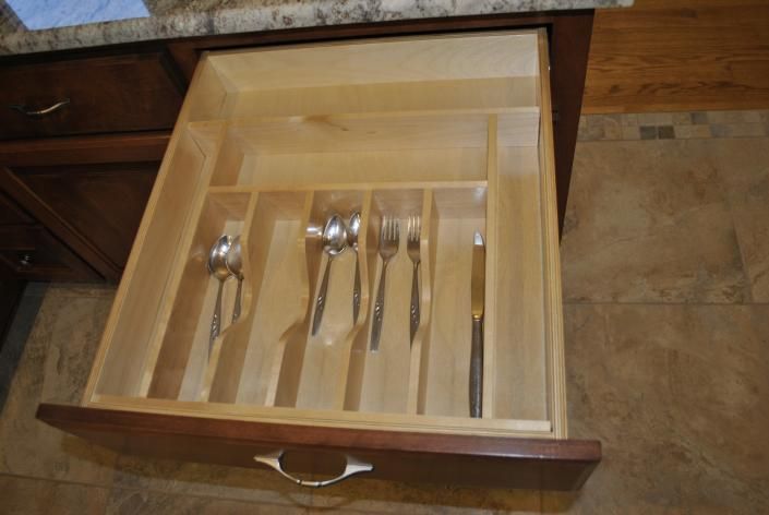 Open kitchen drawer with a wooden silverware organizer containing silverware.